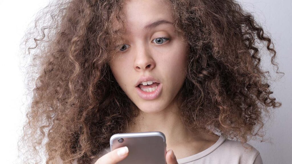 Young girl looking at mobile phone with a surprised look