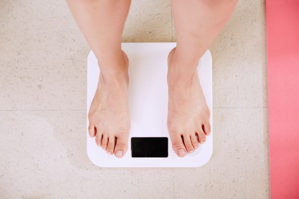 bare legs standing on white bathroom scales