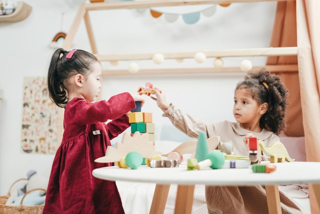 Two young girls playing with wooden blocks in a child's room