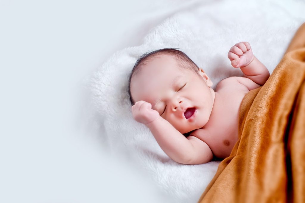 baby-lying-on-white-fur-with-brown-blanket