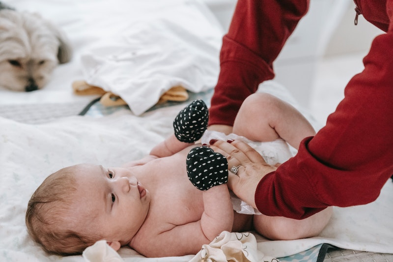 Baby wearing black mittens, having their nappy changed. child-safety-and-nappy-changing