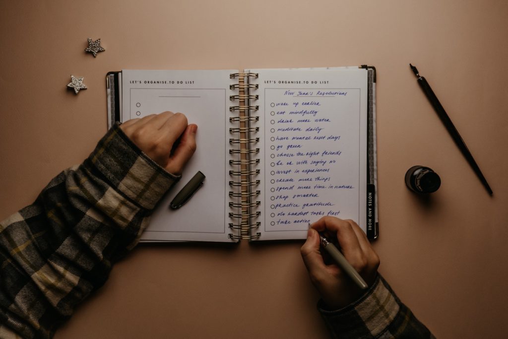 New year new me: Hand writing a list of new year resolutions into open notebook on a table