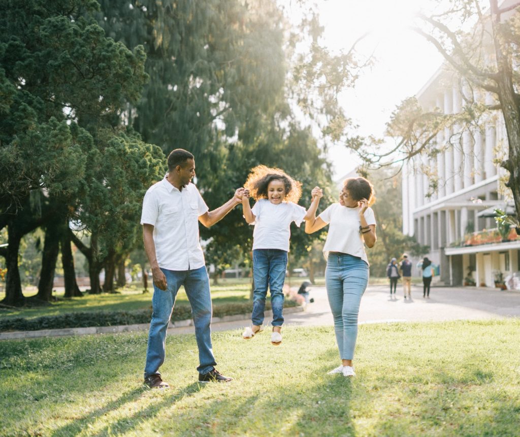 Man and woman holding up a jumping child - co-parenting