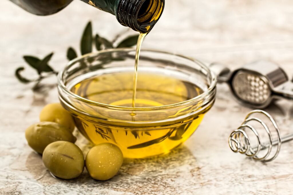 Olive oil being poured into a glass bowl. Massage onto baby's scalp to help get rid of cradle cap.