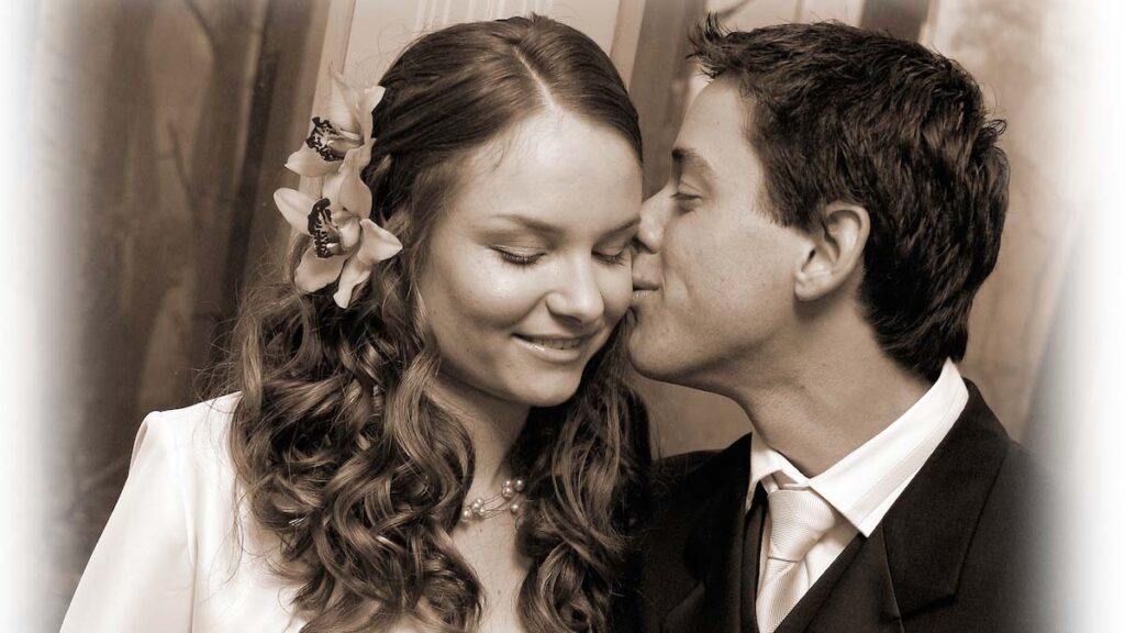 Wedding photo of groom kissing bride on cheek