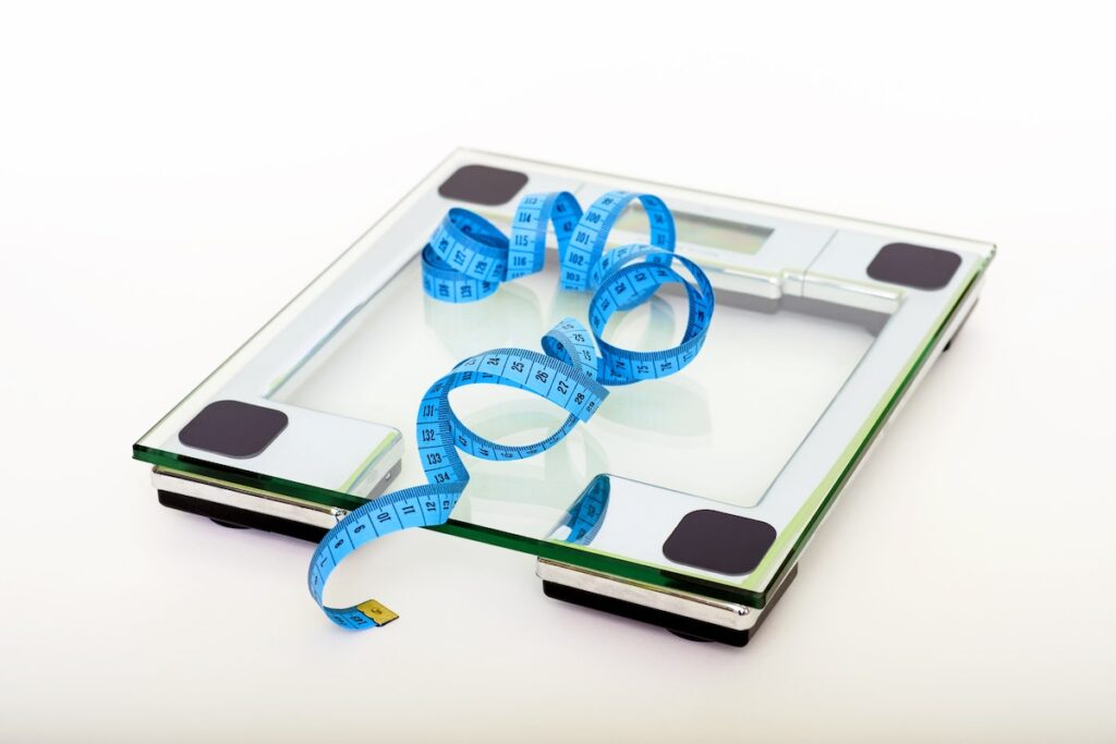 Dressmakers tape measure on a glass weight scales in front of a white background