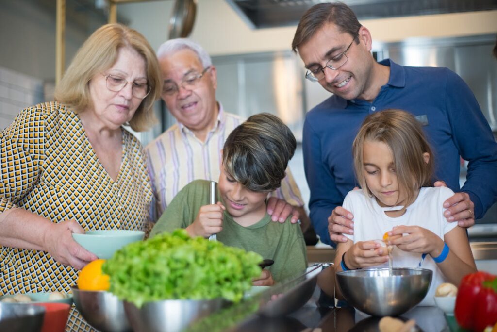 Grandparents and a father looking at two young children trying to prepare something for cooking.